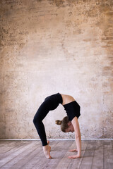 Young girl teenager doing stretching in gym. Blond woman gymnast ballerina in black sportswear dancing. Girl doing acrobatic figures and string. Girl standing on hands