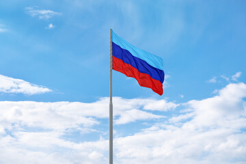 Flag of the self-proclaimed Luhansk People's Republic (LPR or LNR) is waving in front of blue sky and clouds
