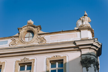 Fototapeta na wymiar Lubomirski Palace in Lviv, Ukraine. The facade of the old baroque house with an oval window and sculptures on the roof in the form of military knightly armor on blue sky background.