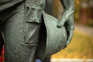 Military helmet in hand. Monument to soldier is in detail.