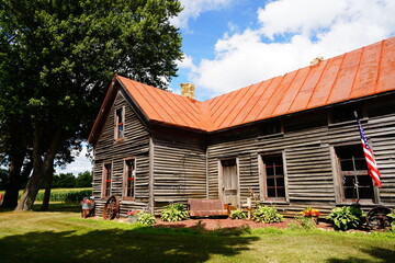 Fototapeta na wymiar A vintage old abandoned wooden log house sits out in the countryside of Green Lake, Wisconsin promoting God Bless America.