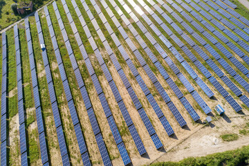 Aerial view of solar power plant on green field. Electric farm with panels for producing clean ecologic energy