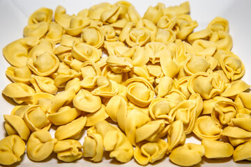 Traditional Italian tortellini (capeletti, agnolini) fresh pasta stuffed with chicken, special for preparing soup on cold nights, isolated on a white background. In depth-of-field blur