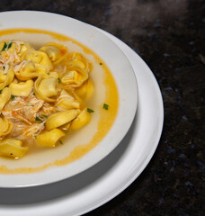 Typical tortellini (capeletti, agnolini) soup with chicken and vegetables, special soup for cold nights. In fine details