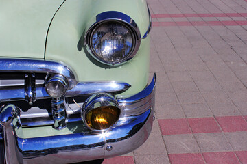 The front lights of an old blue car. The front part of an old car. Front bumper