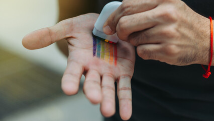 Hands putting on rainbow makeup to celebrate gay pride month.