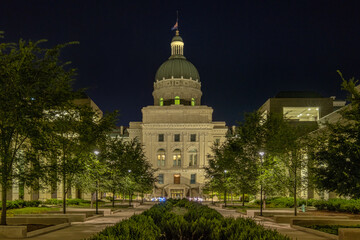 Illuminated Indiana State Capitol: Trees lining the sidewalk and bushes in the central garden enhance the grandeur of this iconic building.