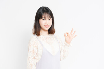 白い背景の前でOKのポーズをする若い女性