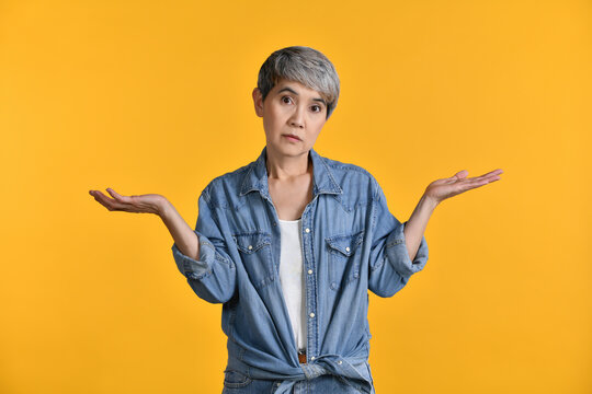 Image Of Confused Puzzled Upset Middle Aged Asian Woman 50s Standing Isolated Over Colour Background. Looking Camera..