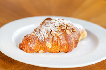 Delicious fresh almond croissant on a plate, perfect addition to the morning coffee