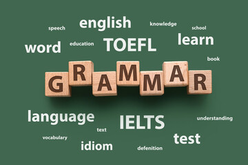 Text GRAMMAR made of wooden cubes and different words on green background. Concept of studying...