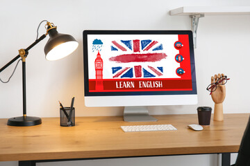 Modern computer with flag of Great Britain and text LEARN ENGLISH on screen at workplace