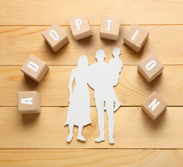 Word ADOPTION made of cubes and figure of family on wooden background