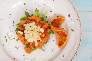 Raw salmon tartare, trout tartar or red fish cubes salad with fresh avocado on white plate and background. Delicious raw tuna tatar or sashimi on white plate restaurant plate top view