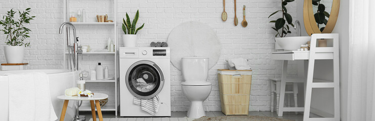 Stylish interior of modern bathroom with bathtub, toilet bowl and washing machine