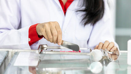 Asian woman pharmacist counting pills at the pharmacy drug store with stainless steel pill counting...