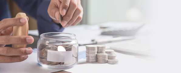 Businessman put a coin in a piggy bank and presses a calculator for money saving planning ideas.