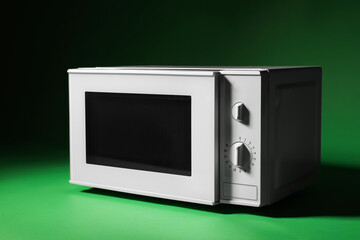 Obraz premium White microwave oven with opened door on green background