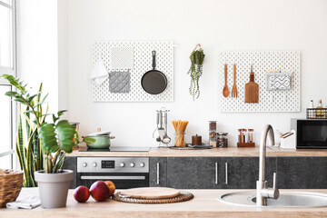 Interior of kitchen with modern counters and pegboards with utensils