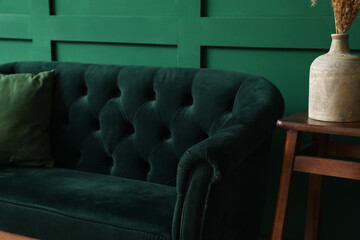 Stylish sofa near green wall