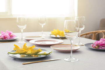 Dining table with beautiful setting, empty glasses and Gladiolus flowers