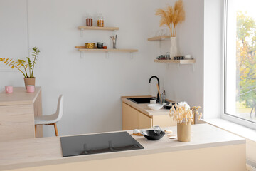 Interior of light kitchen with electric stove and utensils