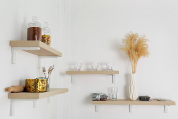 Shelves with kitchenware and vase hanging on light wall