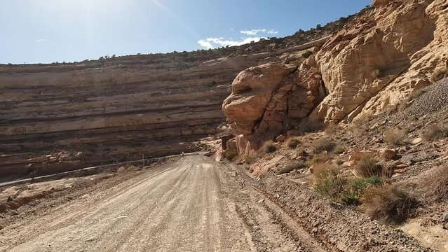 Moki Dugway Utah mountain man jogging POV. Roadway carved from a mountain cliff. Scenic Backway dirt road drastically switches backs the side of a cliff very narrow. Built as mining and uranium road.