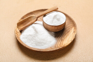 Plate and bowl with baking soda on beige background
