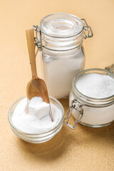 Jars and bowl with baking soda on beige background
