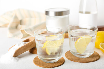 Glasses of water with lemon slices and baking soda on table