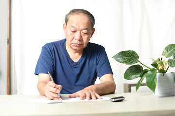 文章を書くアジア人の高齢者男性