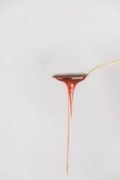 Dripping Caramel From A Gold Spoon On A White Background 