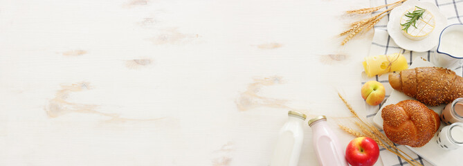 top view photo of dairy products over white wooden background. Symbols of jewish holiday - Shavuot