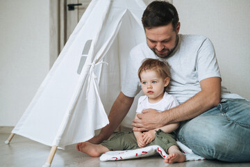 Happy father young man and baby girl little daughter having fun playing in wigwam in children room at home © Galina Zhigalova