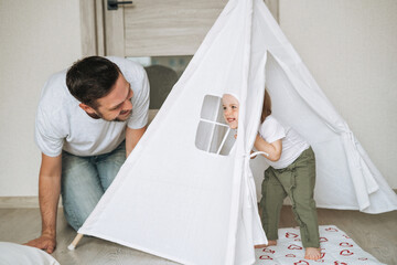 Happy father young man and baby girl little daughter having fun playing in wigwam in children room at home © Galina Zhigalova
