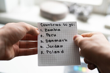 person holding a paper note with countries to visit list