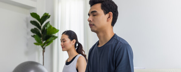 Asian young couple exercise and play yoga together at home background.Concept of Exercise during the quarantine at home for preventing coronavirus and covid-19 infection.