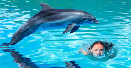 Young girl is having fun experience, swiming with dolphin 
