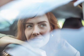 Young Woman Embracing Her New Car. Excited young woman and her new car indoors. Young and cheerful woman enjoying new car hugging steering wheel sitting inside - obrazy, fototapety, plakaty