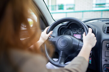 Naklejka premium Beautiful smiling young redhead woman behind steering wheel driving car.
