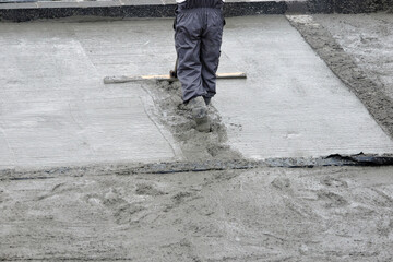  A building worker bull-floating the wet concrete
