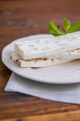 Sliced white nougat with almonds on wooden table