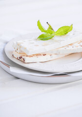 Sliced white nougat with almonds on wooden table