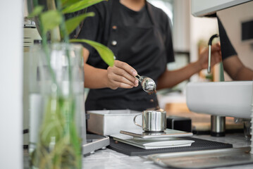 Asian woman Barista making coffee in coffee shop. Happy woman barista working in coffee cafe.