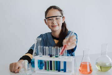 Caucasian girl student learning a chemical experiment in science class. Cute little girl holding test tube while learning chemistry class in white laboratory room.