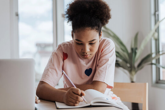 African girl learning class from homel. African american girl learning and doing homework at home.