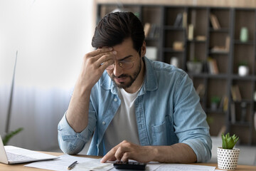 Financial problem. Concerned millennial businessman calculate taxes bills payments deal with debt bankruptcy overdue account. Worried young man accountant unable to form balance sheet look for mistake - obrazy, fototapety, plakaty