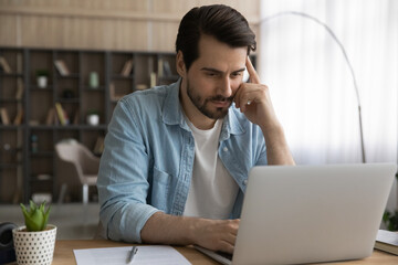 Engaged in work. Thoughtful young man freelancer concentrate on solving business problem using...