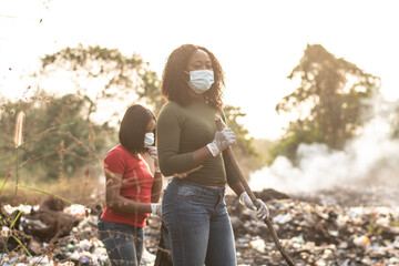 black women cleaning up a dump site - obrazy, fototapety, plakaty